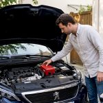 Un automobiliste français en train d’installer un boîtier de conversion E85 sous le capot de sa voiture.