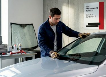 1778842986538_Technician-replacing-car-windshield-in-garage Un technicien procède au remplacement d’un pare-brise dans un atelier automobile.