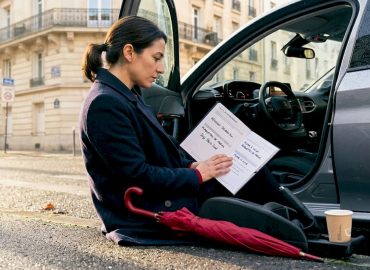 1779797174114_Automobiliste-verifiant-carnet-d-entretien-apres-trajet-court-1 Après avoir parcouru une courte distance, un conducteur consulte son carnet d’entretien pour vérifier l’état de son véhicule.