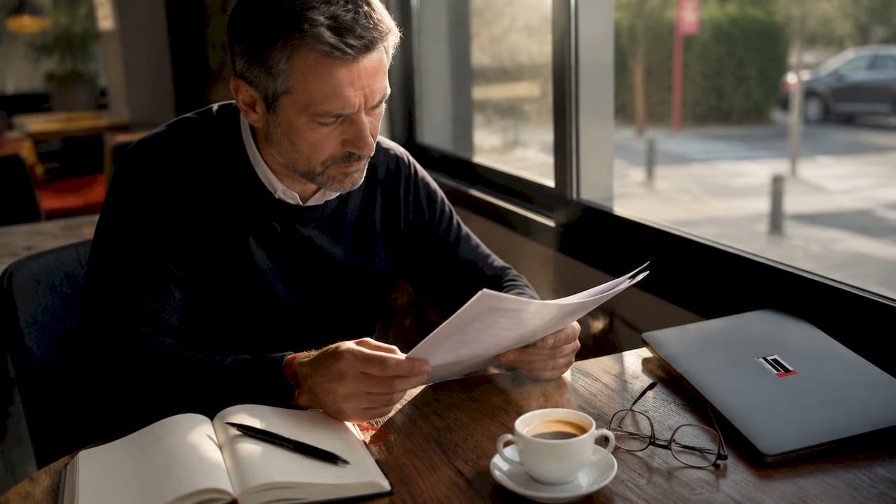 Un homme examine des documents relatifs à la garantie de son moteur.
