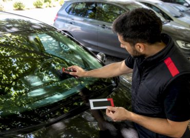 Un technicien contrôle le taux de passage de la lumière à travers une vitre de voiture.