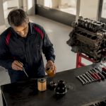 Un mécanicien examine minutieusement les pièces essentielles d’une voiture posées sur son établi.