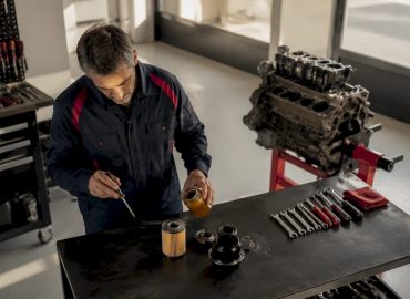 1782711546494_Mechanic-inspecting-essential-car-parts-on-workbench Un mécanicien examine minutieusement les pièces essentielles d’une voiture posées sur son établi.