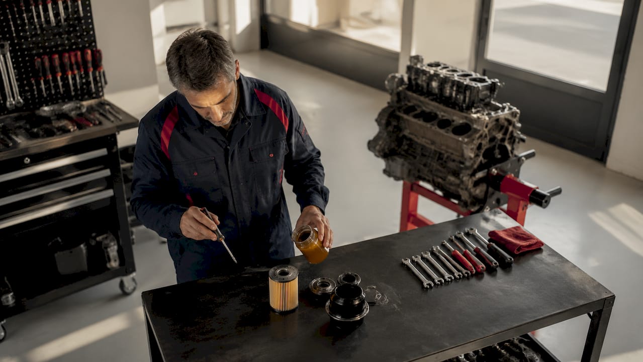 Un mécanicien examine minutieusement les pièces essentielles d’une voiture posées sur son établi.