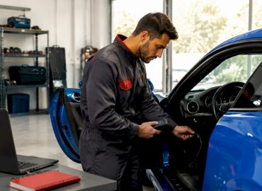 1783063094223_Mechanic-connecting-diagnostic-tool-to-car Un mécanicien branche une valise de diagnostic sur le véhicule.