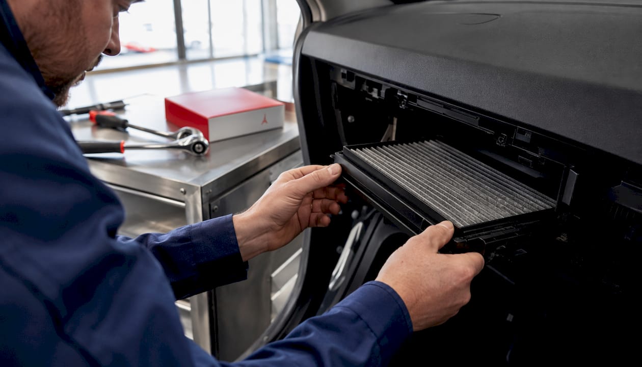 Un technicien procède au remplacement du filtre à pollen dans l’habitacle d’une voiture.