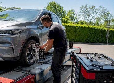 Un spécialiste en atelier procède aux réglages de la géométrie des roues avant pour garantir une tenue de route optimale.