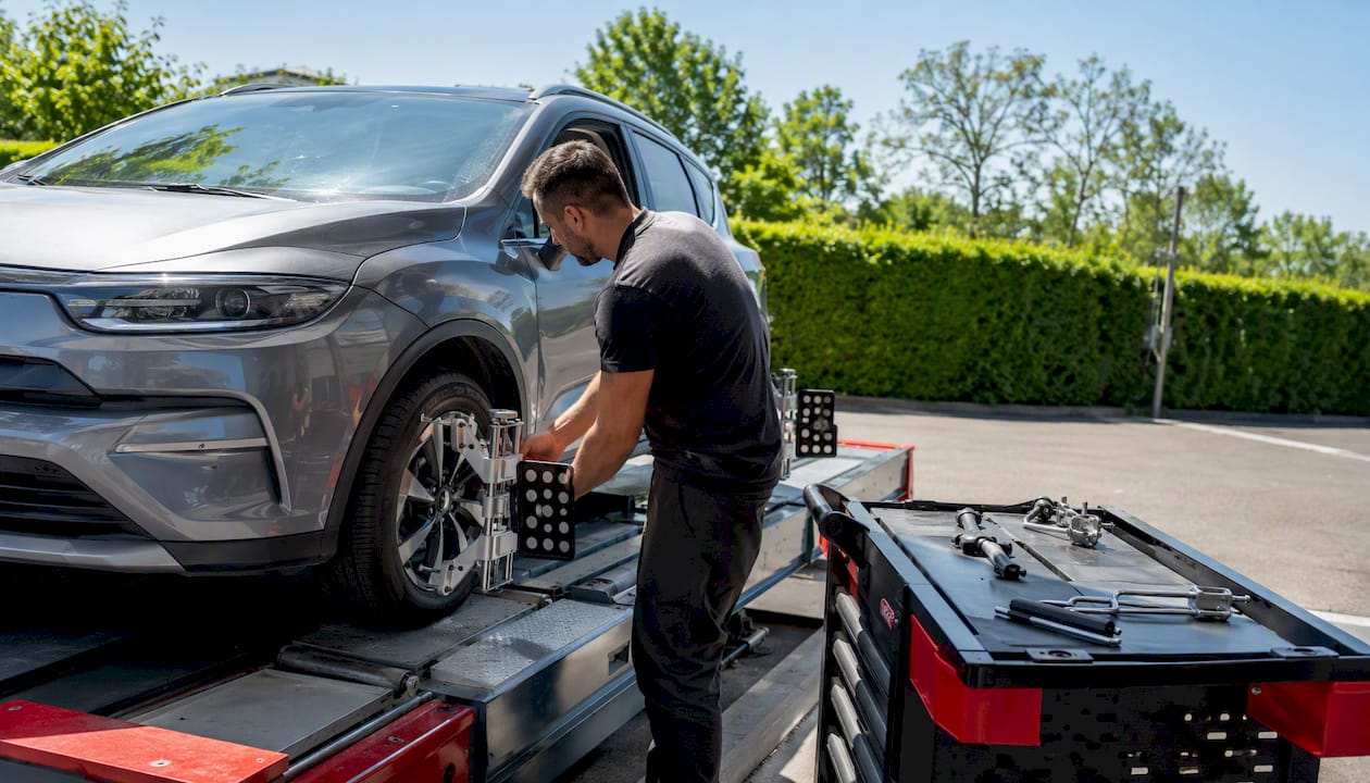 Un spécialiste en atelier procède aux réglages de la géométrie des roues avant pour garantir une tenue de route optimale.