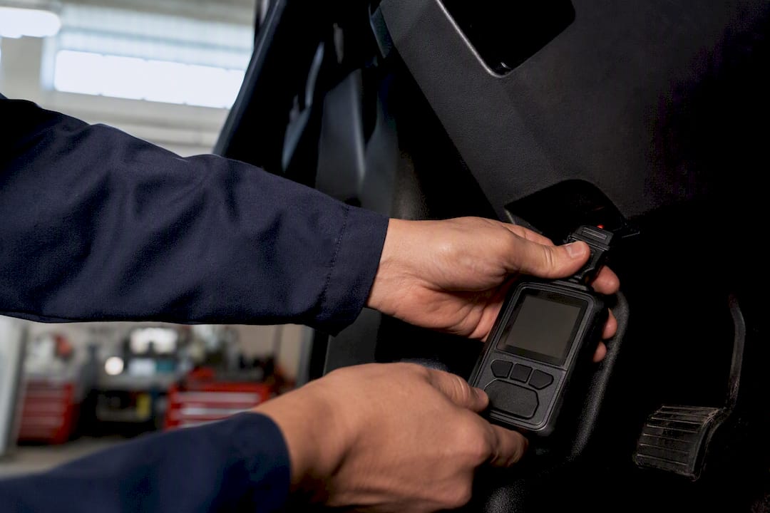 Des mains branchant un scanner OBD2 à la prise du véhicule