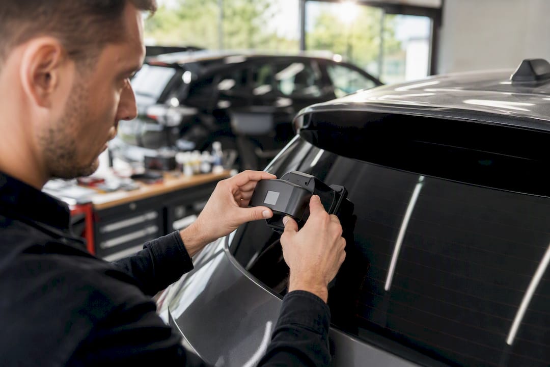 Technicien mesurant la teinte du vitrage d'une voiture avec un appareil