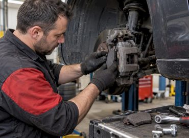 1792238768561_Mechanic-fitting-brake-pads-at-a-wheel-hub Mécanicien installant des plaquettes de frein sur un moyeu de roue